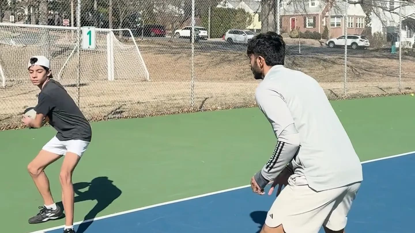 Coach Arun and an adult student side by side in a split step ready position during a footwork drill