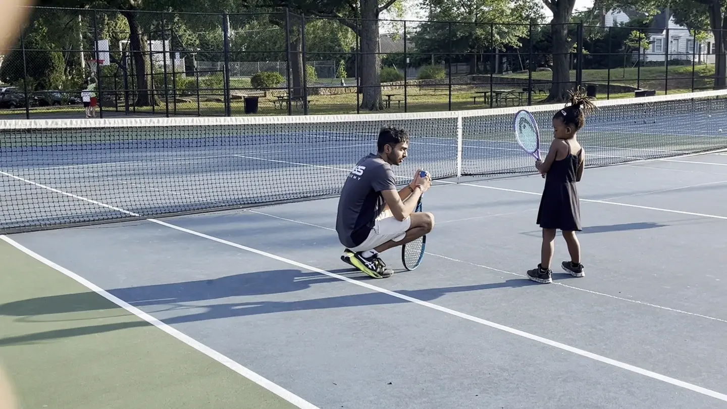 Coach Arun working with a young tennis player on an outdoor court in Northern Virginia